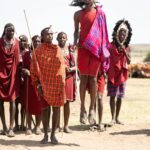 Maasai tribe members performing a traditional jumping dance in Kenya's open landscape.